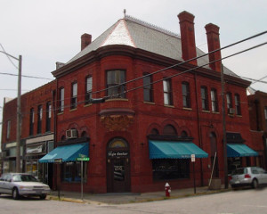 The exterior of a brick commercial building with green awnings and a metal roof.