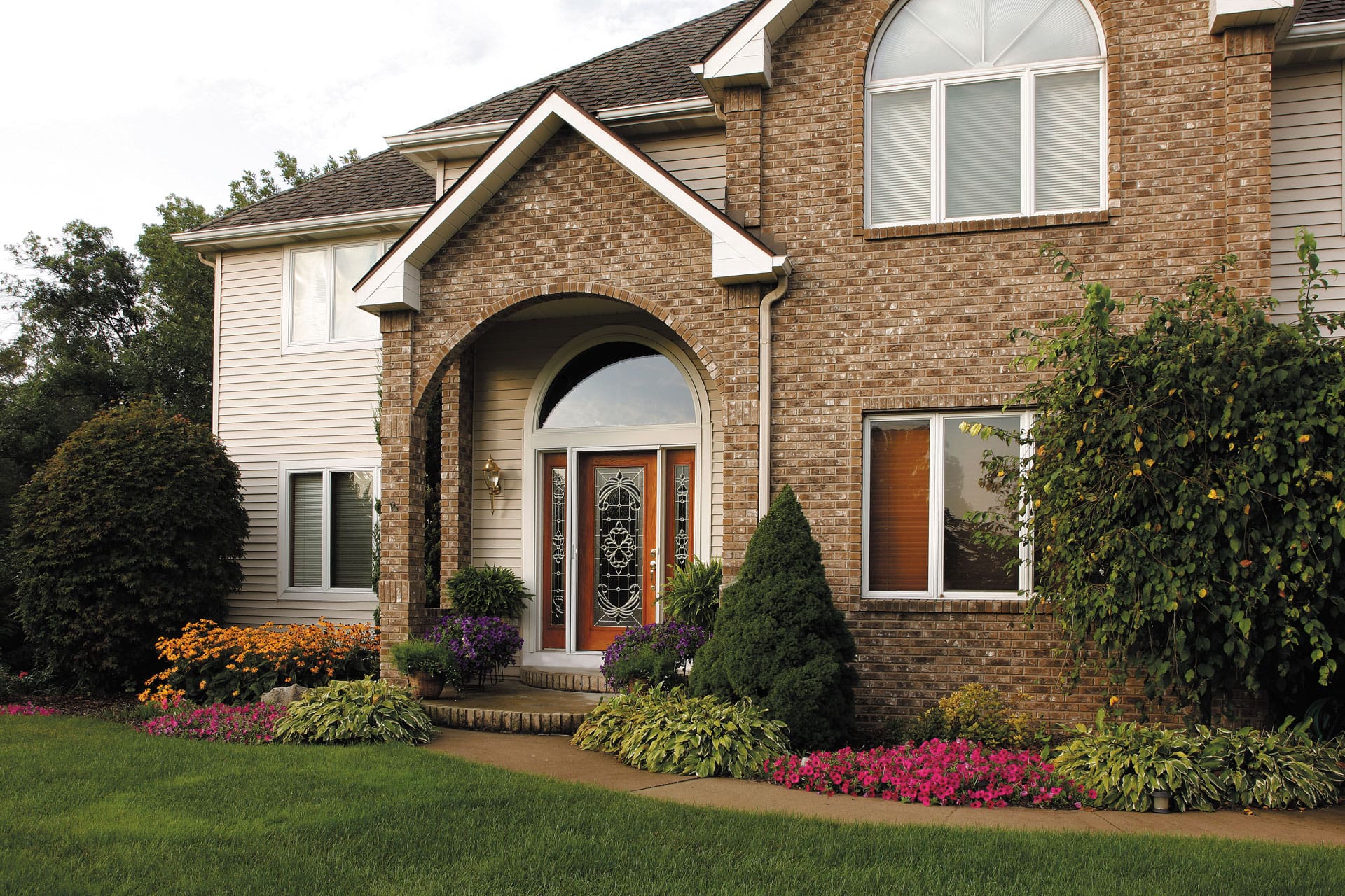 A brick home with a glass entry door with a white frame.